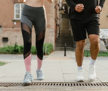 Two adults jogging outdoors, promoting health and fitness in an urban setting.