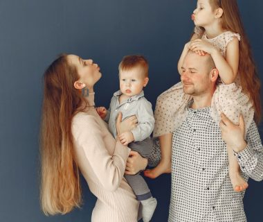 Portrait of a joyful family with parents and kids showing love and affection against a blue background.